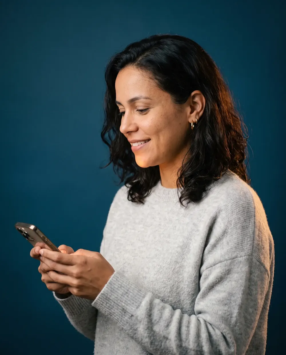 Mulher sorrindo enquanto procura um exame no celular